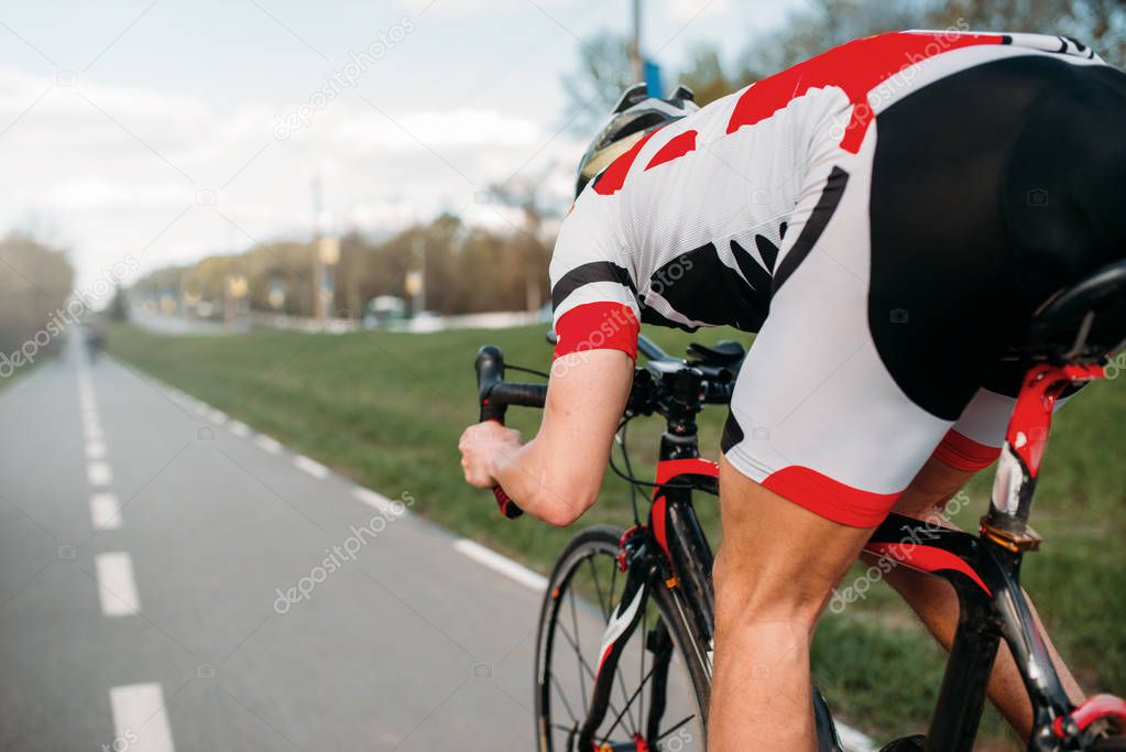 male cyclist in helmet and sportswear riding bicycle, back view 