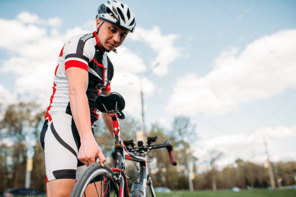 Male cyclist in helmet and sportswear prepares before bike competition. Workout on bike path, bycycle race