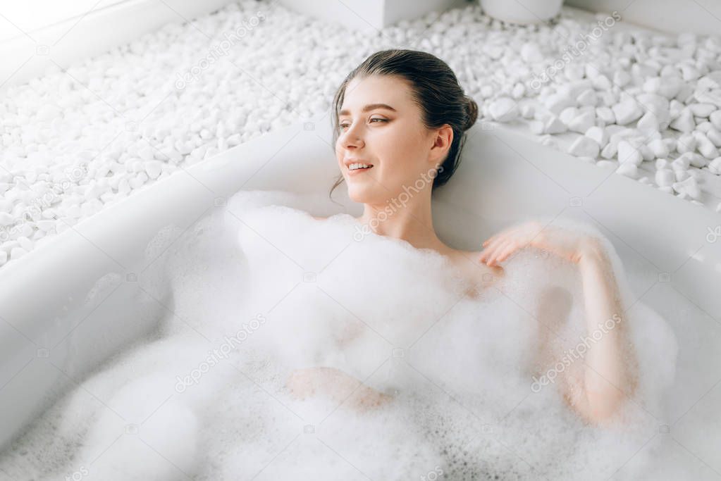 attractive woman lying in bath with foam, relaxation, health and skincare concept