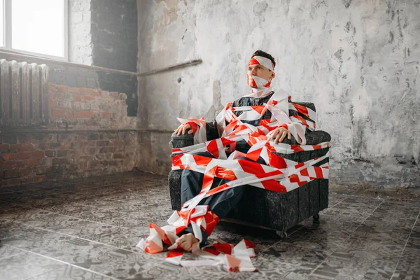 Homem Envolto Fita Cola Sentado Numa Poltrona Sala Grunge Mad — Fotografia de Stock