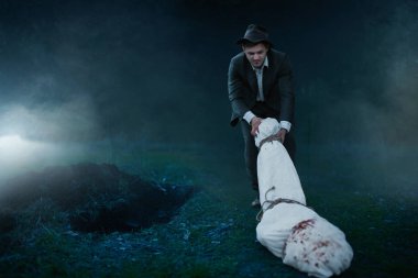 Avcı kurbanın cesedinin sarılı bir tuval içine bir mezar, seri manyak kavramı, gece suç, şiddet sürüyor