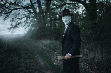 Ormanda, yüz balta ile seri manyak sarılmış bandaj, kanlı katil kavramı, çılgın katil, suç ve şiddet korku