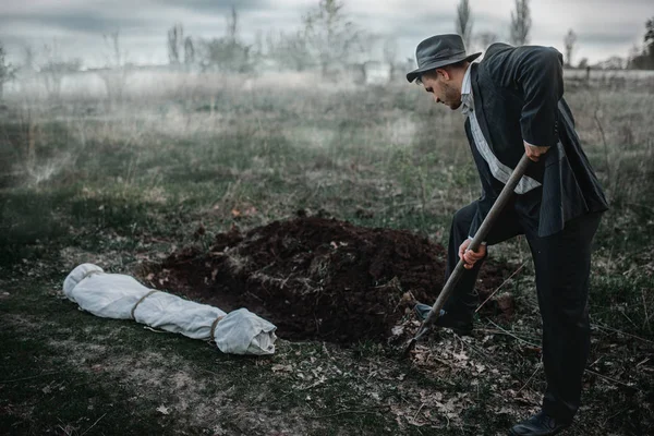 杀手在森林里为受害者挖坟墓尸体裹在画布上连环疯子的概念 — 图库照片
