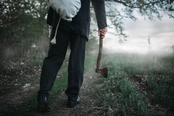 Avcı bir balta ile kurbanın cesedini ormana, seri manyak kavramı bir tuval sarılı taşır