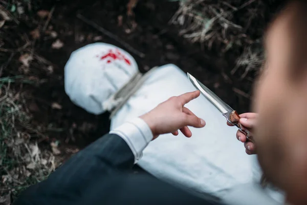 血淋淋的屠宰者用刀对坟墓 受害者包裹在帆布 连环杀人犯概念 犯罪恐怖 — 图库照片
