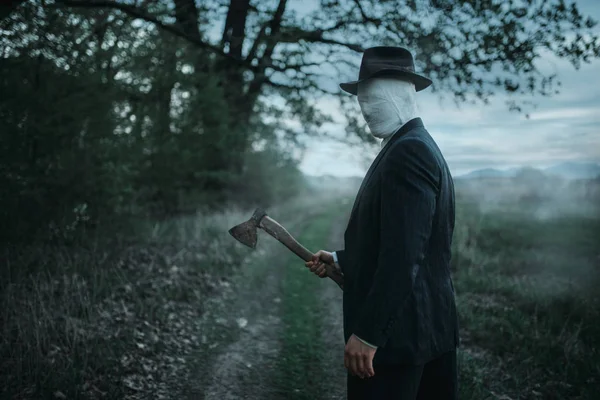 Ormanda, yüz balta ile seri manyak sarılmış bandaj, kanlı katil kavramı, çılgın katil, suç ve şiddet korku