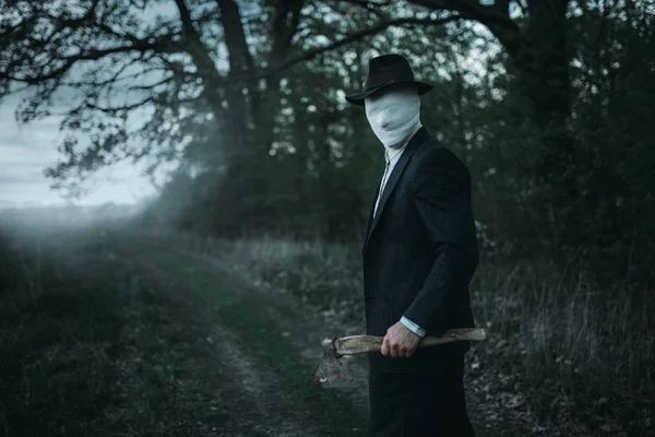 Ormanda, yüz balta ile seri manyak sarılmış bandaj, kanlı katil kavramı, çılgın katil, suç ve şiddet korku