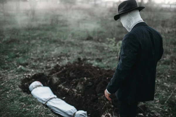 Kanlı katil kurbanı ormandaki bir tuval, seri manyak kavramı sarılı beden ile bir mezar karşı duruyor