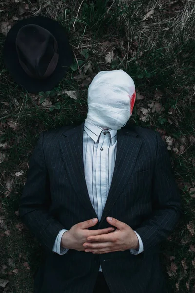 Orman, çılgın katil kavramı, psikopat katil yere kanlı bandaj yatıyor sarılı yüzü ile seri manyak