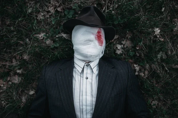 Orman, çılgın katil kavramı, psikopat katil yere kanlı bandaj yatıyor sarılı yüzü ile seri manyak