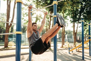 Açık alan fitness egzersiz bar, yatay kullanarak abs egzersiz yapan atletik erkek. Güçlü sporcu spor eğitim Parkı