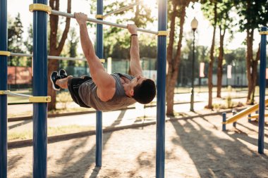 Açık alan fitness egzersiz bar, yatay kullanarak abs egzersiz yapan atletik erkek. Güçlü sporcu spor eğitim Parkı