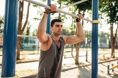 Yatay çubuklar üzerinde açık alan fitness egzersiz eğitim Erkek atlet. Yaz Park güçlü sporcu