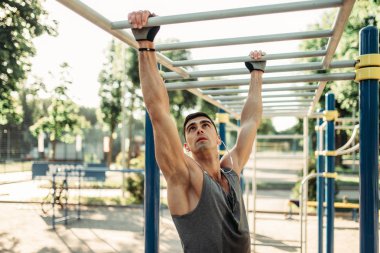 Yatay çubuklar üzerinde açık alan fitness egzersiz eğitim Erkek atlet. Yaz Park güçlü sporcu