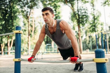 Açık alan fitness egzersiz bar, yatay kullanarak push-up egzersiz yapan atletik erkek. Güçlü sporcu spor eğitim Parkı