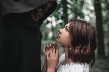 Kadın kurban orman arka plan üzerinde siyah bir hoodie ölüm gözlerinin içine bakar. Korku tarzı, gizem ritüel fotoğraf