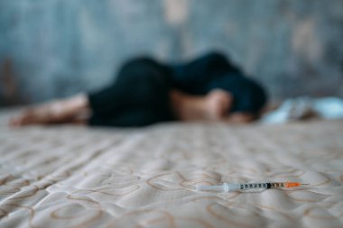 Kadın keş elinde doz sonra yatakta uyuyan şırınga ile. Uyuşturucu bağımlılığı kavramı, insanlar uyuşturucu bağımlısı