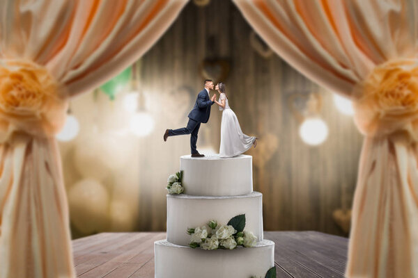 Wedding cake with bride and groom on the top. Pie for newlyweds with little figurines, love symbol