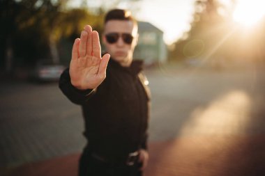 Ciddi polis memuru üniforma ve güneş gözlüğü el dur işareti, önden görünüm gösterir. İş yerinde polis. Hukuk koruma kavramı, Emanet denetim iş