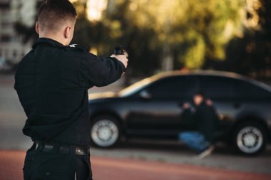 Polis memuru elinde silahla araba hırsızı tutuklama. İş yerinde polis. Hukuk koruma kavramı, profesyonel güvenlik denetimi