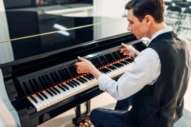 Erkek piyanist siyah kuyruklu piyano klavye kapağını açar. Müzisyen royale, klasik müzik aleti performansına hazırlar