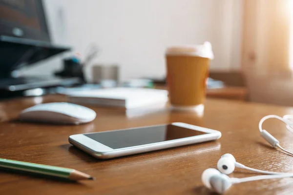 白の電話 ヘッドフォン マウスとオフィスのクローズ アップ 木のテーブルにコーヒー カップ誰も 現代のビジネスの職場 — ストック写真