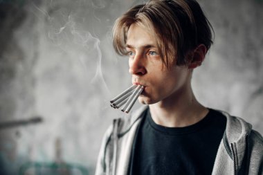 Birçok sigara ağzında ulaşan onun el ileri, grunge arka plan ile genç esrarkeş. Hiçbir yasaktır kavramı, uyuşturucu bağımlısı