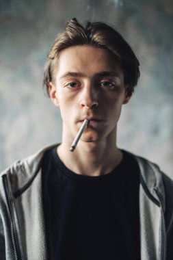 Genç adam Sigara İçilmeyen, grunge arka plan. Bağımlılık kavramı, sigara uyuşturucu