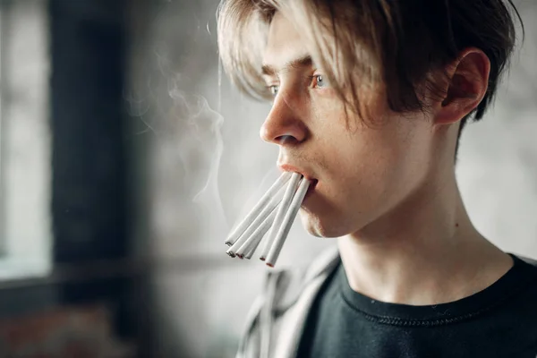 年轻的瘾君子 嘴里叼着许多香烟 伸手向前 垃圾的背景 不吸烟概念 瘾君子 — 图库照片