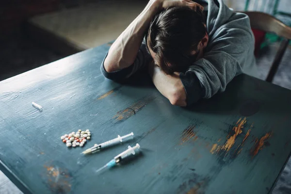 男性吸毒者坐在餐桌前用毒品和注射器 室内的垃圾室背景 吸毒成瘾的概念 上瘾的人 — 图库照片