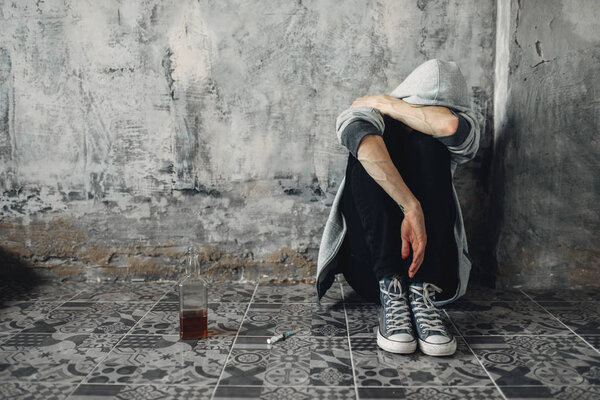 Depressed druggy sitting on the floor, withdrawal symptom. Narcotic addiction concept, drug addicted people