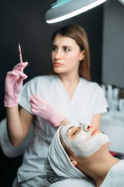 Şevval özçelik güzellik kadın hasta, botox enjeksiyon kırışıklıklar, kozmetik klinik kurtulmak karşı elinde şırınga. Yüz cilt bakımı, gençleştirme yordamı spa salonda, sağlık