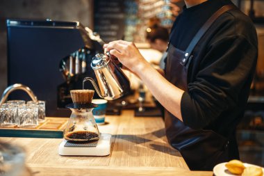Erkek barista kahve, Cafe counter arka plan üzerinde cam içine kaynar su dökülen. Barmen barmen işgal kafeteryasında tarafından profesyonel espresso hazırlık