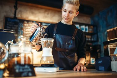Genç erkek barista latte, Cafe counter ve espresso makinesi arka plan üzerinde Barmen kafeteryada çalışıyor, barmen kahve hazırlar