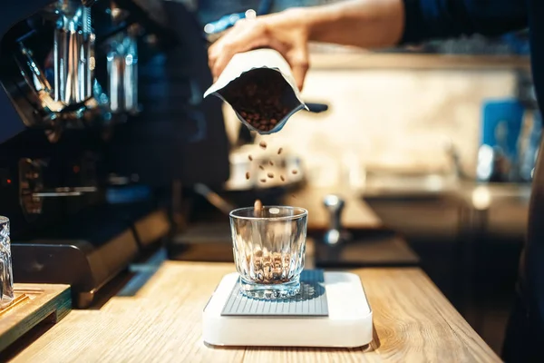 Barista el kahve çekirdekleri cam, arka plan üzerinde Cafe counter içine dökülen. Profesyonel espresso hazırlık kafeterya barmen tarafından