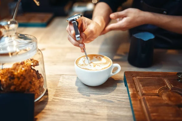 男性バリスタ コーヒーの泡を図面になります バーテンダーの背景に木製のカウンターによるプロ カプチーノ作製 — ストック写真