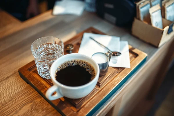 新鮮なブラック コーヒー 水のガラスのカップにエスプレッソ カフェ バック グラウンド カフェテリア内部に木製のカウンターに立っている誰も — ストック写真