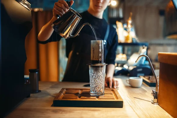 男性のバリスタは ガラス カフェ カウンター 背景にエスプレッソ マシンにコーヒー ポットからお湯を注ぐ バーマンは カフェテリア バーテンダーの職業 — ストック写真