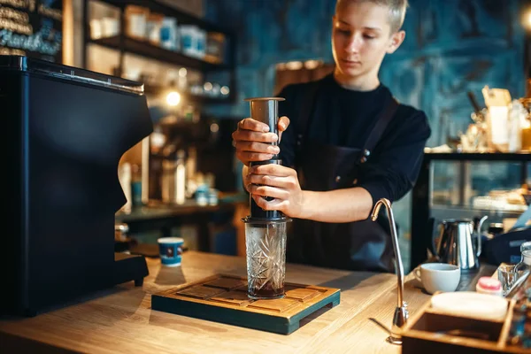 男性のバリスタは ガラス カフェ カウンター 背景にエスプレッソ マシンにコーヒー ポットからお湯を注ぐ バーマンは カフェテリア バーテンダーの職業 — ストック写真