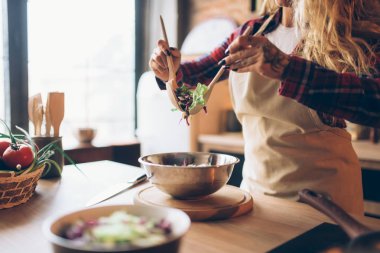 Ev kadını yemek taze salata, mutfak iç arka plan üzerinde önlük. Mutlu kadın aşçı. Şef tarafından gıda hazırlama