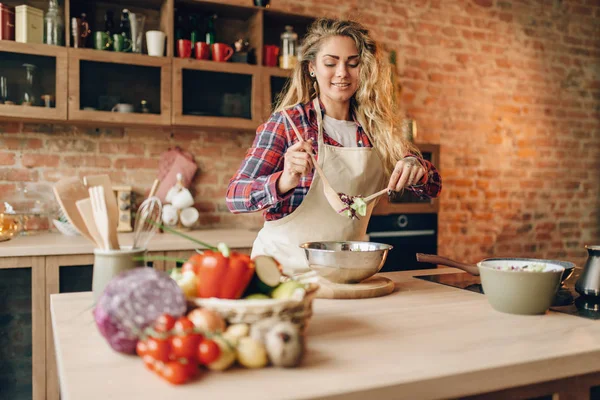 エプロンの女性コックは 新鮮なサラダ 背景にキッチン インテリアを準備します 健康的なベジタリアン料理 野菜の準備を作っている主婦 — ストック写真