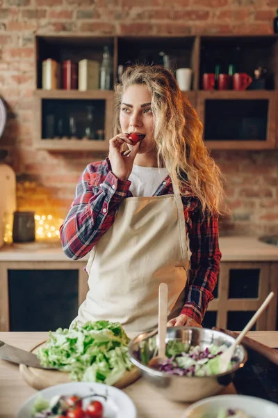 エプロンで幸せな主婦は台所のテーブルに座っているし トマトを手で保持しています 健康的なベジタリアン料理 野菜の準備を作る女性のクック — ストック写真