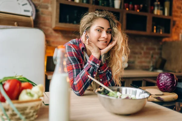 エプロンの中幸せな主婦は 新鮮なサラダ 背景にキッチン インテリアを準備します 笑顔の女性コック 健康的な素食料理 — ストック写真