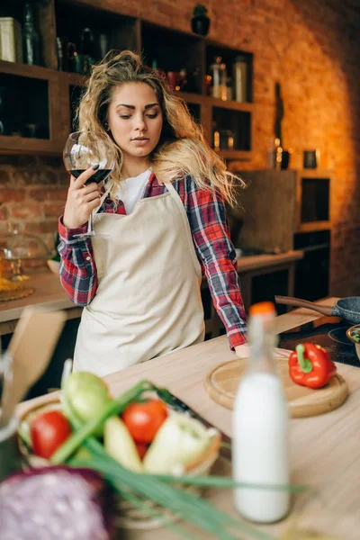 Счастливая Домохозяйка Фартуке Бокалом Красного Вина Руках Кухонный Интерьер Заднем — стоковое фото