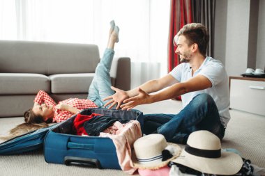 Genç çift tatil için onların bavul ambalaj. Yolculuk kavramı ücretleri. Bagaj hazırlık