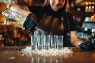 Eldiven kadın barmen içecekler buz üzerinde koyar. Barda karıştırma kadın barmen sayaç pub. Barmen işgal