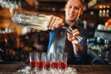 Önlük erkek barmen alkollü kokteyl, buzun içinde ayakta gözlük hazırlar. Barda barmen sayaç pub. Barmen işgal