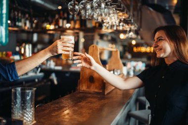 Erkek barmen bir bardak bira kadın ziyaretçiye geçer. Barmen işgal, barmen ve kadın Bar counter