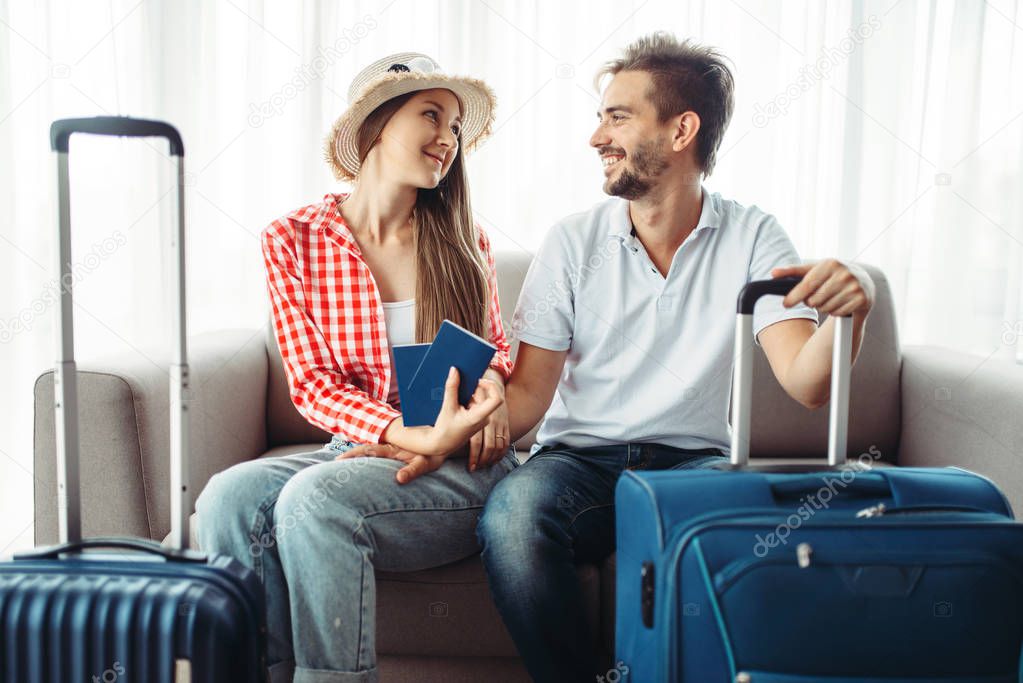Young couple with suitcases ready for journey. Woman holding tickets