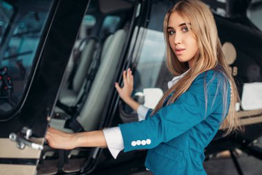Kadın uçuş görevlisi helikopter kabin hangarda karşı teşkil etmektedir. Hostes yakınındaki helikopter üniformalı. Özel hava yolu taşımacılığı